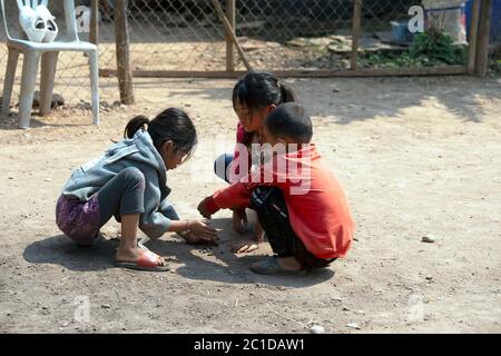 Bambini Hmong giovani, indigeni, etnici che giocano i marmi nel loro villaggio nella provincia di Luang Nontha, Laos settentrionale. Foto Stock