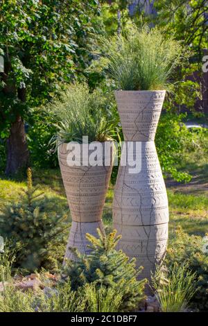 Un'alta pentola rotonda per piante nel giardino, con erba che cresce all'interno dell'erba Foto Stock