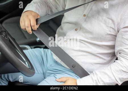 Sedersi sul sedile dell'auto e allacciare la cintura di sicurezza Foto Stock