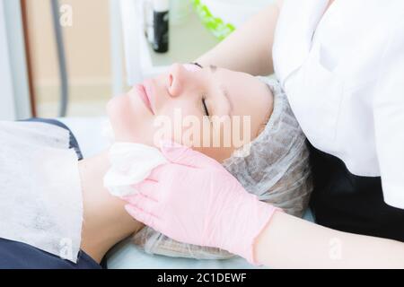 Un primo piano della procedura di pulizia nell'ufficio di cosmetologia. Le mani del cosmetologo in guanti rosa vengono rimosse Foto Stock