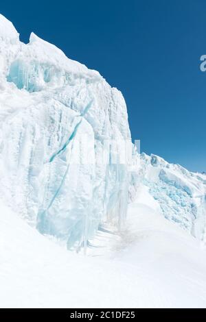 Un grande ghiacciaio innevato alto tra le montagne sullo sfondo delle montagne del Caucaso e cielo blu Foto Stock