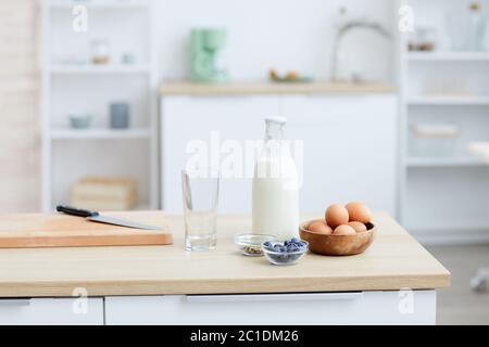 Primo piano di uova di latte e bacche sul tavolo in cucina a casa Foto Stock