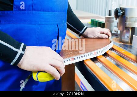 Primo piano delle mani del carpentiere con un metro in un laboratorio di cottage Foto Stock