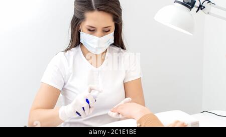 Manicure sta applicando antisettico sulle mani del cliente in manicure salone. Foto Stock