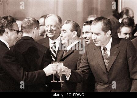 Il presidente AMERICANO Nixon raggiunge per strigliare il suo bicchiere con quello di Henry Kissinger a Mosca nel 1972 con il leader dell'URSS Leonid Brezhnev sullo sfondo Foto Stock