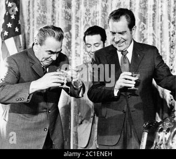 Il presidente AMERICANO Nixon raggiunge per strigliare il suo bicchiere con quello di Henry Kissinger a Mosca nel 1972 con il leader dell'URSS Leonid Brezhnev sullo sfondo Foto Stock