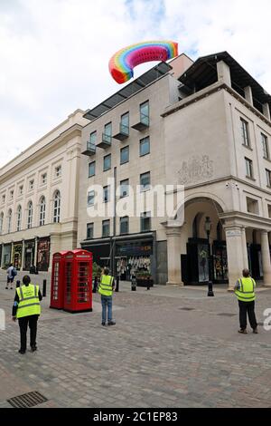 Londra, Regno Unito. 15 giugno 2020. Il mercato di Covent Garden ha volato un arcobaleno sopra il mercato famoso in tutto il mondo 'riconoscendo il ruolo del simbolo di speranza riconosciuto a livello mondiale negli ultimi tempi, e accogliendo i londinesi di ritorno in città, mentre i negozi di tutta la capitale iniziano ad aprirsi' dopo il blocco di Coronavirus. Purtroppo, mentre veniva abbassata dai lavoratori, si impigliava negli edifici opposti. Fortunatamente i lavoratori qualificati sono riusciti a liberarlo prima di riportarlo a terra. Credit: Paul Brown/Alamy Live News Foto Stock