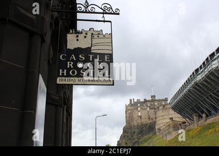 Edimburgo, Scozia - 25 luglio 2015: Segno di sospensione di Castle Rock Hostel con Castello di Edimburgo sullo sfondo in una giornata nuvolosa. Foto Stock