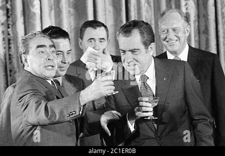 Il presidente AMERICANO Nixon raggiunge per strigliare il suo bicchiere con quello di Henry Kissinger a Mosca nel 1972 con il leader dell'URSS Leonid Brezhnev sullo sfondo Foto Stock