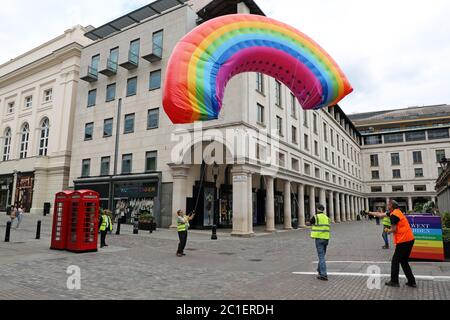 Londra, Regno Unito. 15 giugno 2020. Il mercato di Covent Garden ha volato un arcobaleno sopra il mercato famoso in tutto il mondo 'riconoscendo il ruolo del simbolo di speranza riconosciuto a livello mondiale negli ultimi tempi, e accogliendo i londinesi di ritorno in città, mentre i negozi di tutta la capitale iniziano ad aprirsi' dopo il blocco di Coronavirus. Purtroppo, mentre veniva abbassata dai lavoratori, si impigliava negli edifici opposti. Fortunatamente i lavoratori qualificati sono riusciti a liberarlo prima di riportarlo a terra. Credit: Paul Brown/Alamy Live News Foto Stock