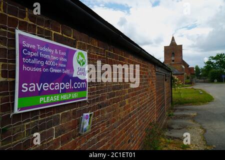 Salva Capel campagna poster nel villaggio di Tudeley protestando contro il piano di Tunbridge Wells Borough Consiglio per costruire oltre 4.000 case a Tudeley e Capel nei prossimi anni in un 'villaggio giardino' sviluppo. Gli abitanti del luogo dicono che il progetto, che si trova sulla terra designata Green Belt, è di gran lunga superiore a quello che la parrocchia rurale di Capel e le sue infrastrutture possono affrontare. L'area si trova anche ai margini della Medway Valley e in una zona alluvione ad alto rischio. Sono previsti anche nuovi e grandi sviluppi di abitazioni per i vicini Five Oak Green e Paddock Wood. La chiesa di tutti i Santi è sullo sfondo. Kent, Inghilterra Foto Stock