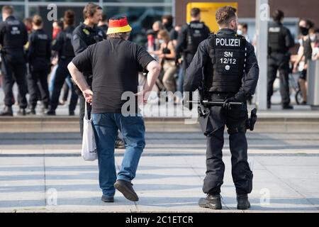 Dresda, Germania. 15 giugno 2020. Un partecipante ad un rally del movimento islamista e xenofobo Pegida indossa un cappello nei colori della bandiera nazionale tedesca mentre si trova accanto ad un poliziotto sull'Altmarkt e guarda una contromundimostrazione. La rete d'azione "Lipsia prende posto" aveva chiesto proteste contro Pegida. Credit: dpa/dpa-Zentralbild/dpa/Alamy Live News Foto Stock