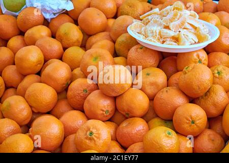 Tangerini per la vendita su un mercato con alcuni pezzi su una piastra Foto Stock