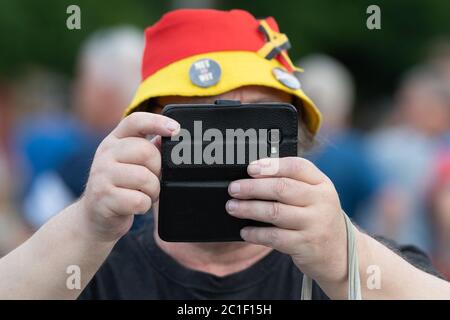 Dresda, Germania. 15 giugno 2020. Un partecipante di un rally del movimento islamista e xenofobo di Pegida tiene uno smartphone sull'Altmarkt. La rete d'azione "Lipsia prende posto" ha chiesto proteste contro Pegida. Credit: dpa/dpa-Zentralbild/dpa/Alamy Live News Foto Stock