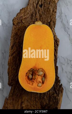 1/2 una zucca di butternut, su legno e su fondo di marmo Foto Stock