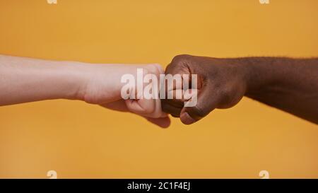 Fist to Fist - mani bianche e nere - concetto di partenariato e solidarietà. Foto di alta qualità Foto Stock