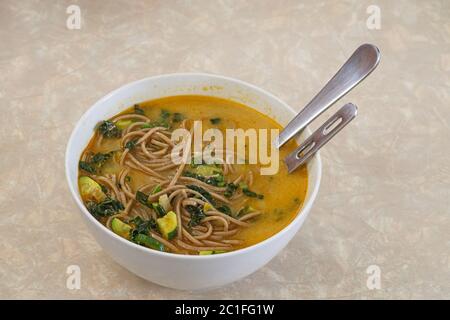 ciotola di zuppa fatta in casa con verdure ricche di brodo e tagliatelle di soba Foto Stock