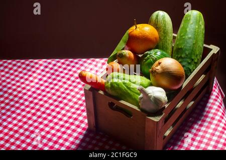 Cassa di frutta e verdura con zucchine, chayote, mandarino, carote, cetriolo, melanzane scarlatto, cipolla e aglio. Foto Stock