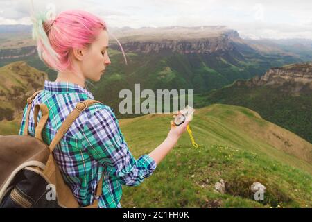 Una ragazza hipster viaggiò con un blogger in una camicia plaid e con capelli multicolore usando una bussola sullo sfondo nel bac Foto Stock