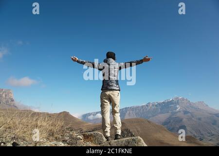 un applauso di una giovane donna saccopelatrice in cima a una vetta di montagna che si stira. Libertà e vittoria sullo sfondo o Foto Stock