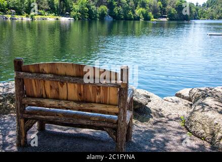 Panca vuota di legno sulla costa del lago Mohonk, nella parte settentrionale dello stato di New York. Foto Stock