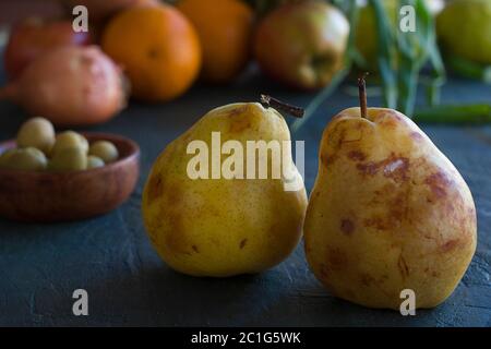 alcune pere e altri frutti su un tavolo scuro Foto Stock
