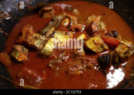 Meen Vatichathu o Pattichathu, pesce sardino cotto. Curry tradizionale di pesce caldo e piccante Kerala India con foglie di curry rosso e verde. Foto Stock