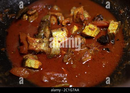 Meen Vatichathu o Pattichathu, pesce sardino cotto. Curry tradizionale di pesce caldo e piccante Kerala India con foglie di curry rosso e verde. Foto Stock