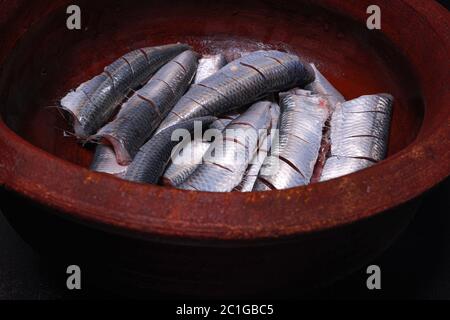 Sardine fresche tagliate testa ed essendo preparati per cucinare il kerala indiano del sud sugo e friggere fatti in casa Foto Stock