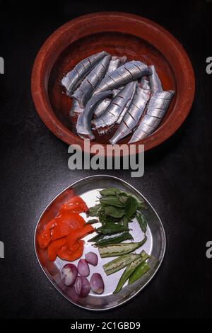 Sardine fresche tagliate testa ed essendo preparati per cucinare il kerala indiano del sud sugo e friggere fatti in casa Foto Stock