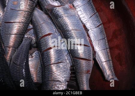 Sardine fresche tagliate testa ed essendo preparati per cucinare il kerala indiano del sud sugo e friggere fatti in casa Foto Stock