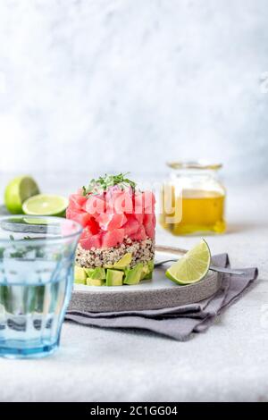 Tartare di tonno con avocado e quinoa. Presentazione gourmet con anello culinario su piatto di wite Foto Stock