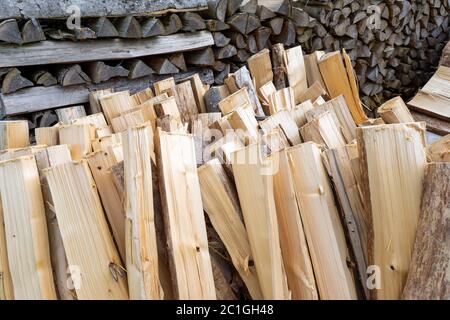 Tronchi lunghi verticali di legna da ardere appena lavorata di fronte ad un vecchio palo di legno grigio Foto Stock