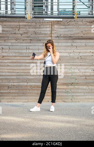 Bella giovane donna che prende il selfie di vanità all'aperto in estate. Scatto lungo. Foto Stock