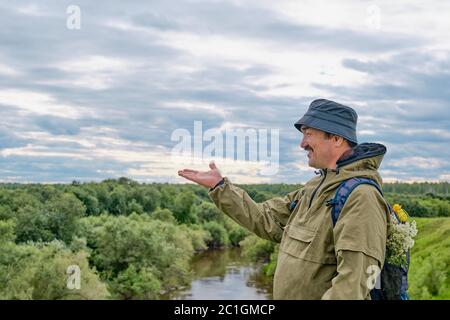 Attivo uomo anziano asiatico con zaino in trekking vicino al fiume in siberia, russia. Viaggi da solo, stile di vita. Foto Stock