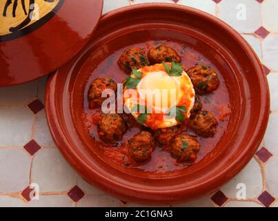 Cibo marocchino. Tipico tajine di argilla con kefta di polpette di agnello e uovo in camicia nella salsa. Foto Stock