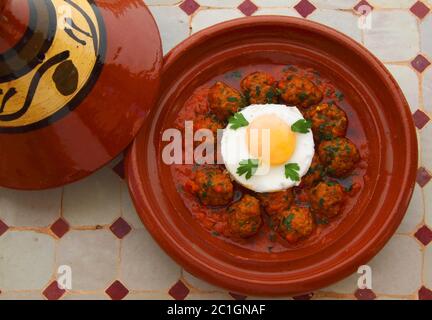 Cibo marocchino. Tipico tajine di argilla con kefta di polpette di agnello e uovo in camicia nella salsa. Foto Stock