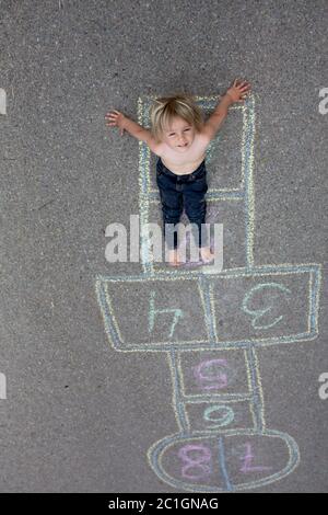 Bambino, ragazzo biondo, giocando a lupposscotch per strada, in estate Foto Stock