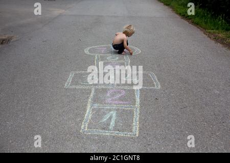 Bambino, ragazzo biondo, giocando a lupposscotch per strada, in estate Foto Stock