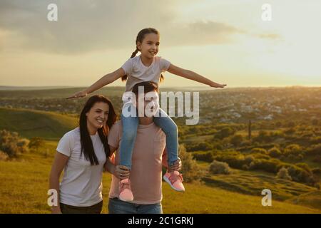 Famiglia in natura. Felice giovane famiglia a piedi in campagna al tramonto. Foto Stock