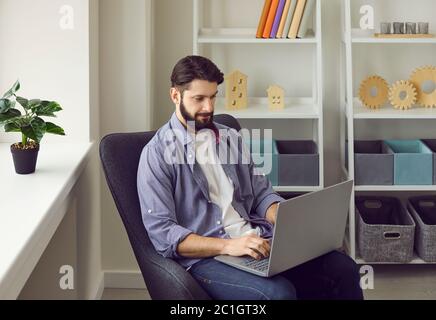 Uomo d'affari che utilizza un computer portatile per lavorare in remoto in ufficio. Il manager maschile naviga su Internet per informazioni online Foto Stock