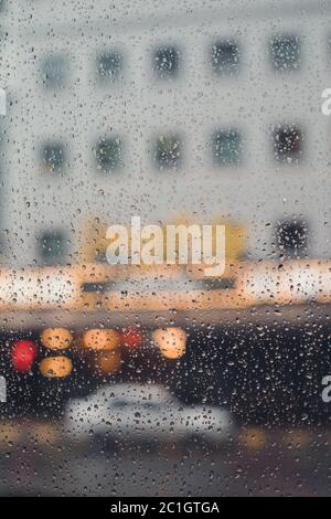 Gocce di pioggia su una finestra che si affaccia su un edificio e un'auto Foto Stock