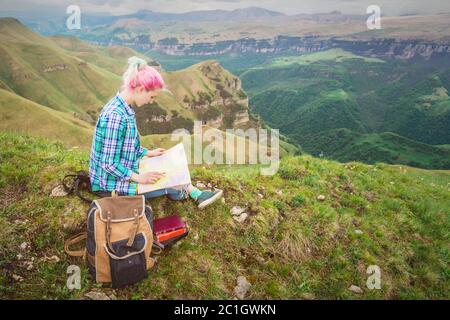 Ragazza viaggiatore con capelli multicolore seduto sulla carta da lettura natura e tenendo una bussola in mano. Il concetto di navigazione th Foto Stock