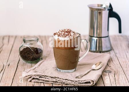 Caffè ghiacciato con panna montata e gocce di cioccolato su tavolo di legno, fuoco selettivo Foto Stock