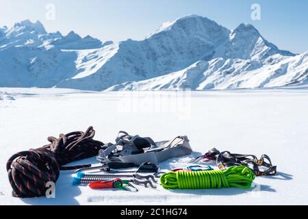 Set invernale di attrezzature di un arrampicatore con ferite da moschettone e un campo thermos sullo sfondo di montai innevati Foto Stock