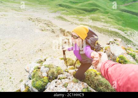 Un arrampicatore aiuta una giovane alpinista a raggiungere la cima della montagna. Un uomo dà una mano di aiuto ad una donna. Vista dall'alto Foto Stock