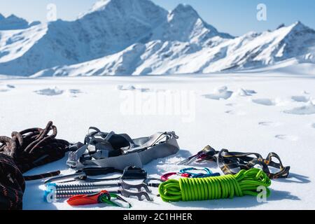 Set invernale di attrezzature di un arrampicatore con ferite da moschettone e un campo thermos sullo sfondo di montai innevati Foto Stock