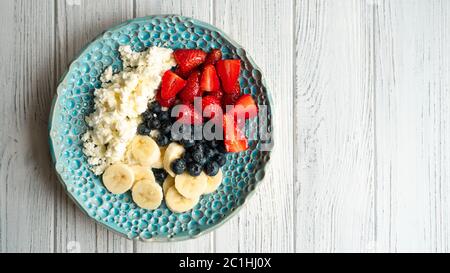 Sana colazione estiva. Formaggio di cottage con fragola mirtillo banana e miele. La colazione era bellissima Foto Stock