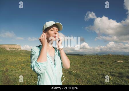 Donna corridore di fitness che chiude gli occhi ascoltando musica sulla natura. Ritratto di bella ragazza che indossa auricolari e. Foto Stock