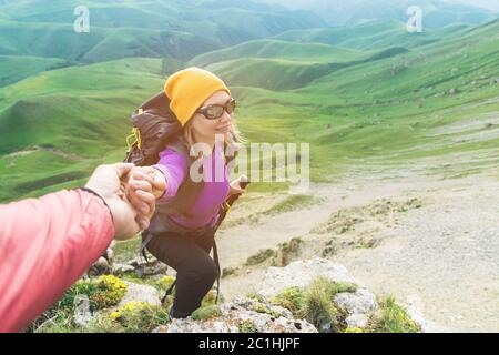 Un arrampicatore aiuta una giovane alpinista a raggiungere la cima della montagna. Un uomo dà una mano di aiuto ad una donna. Vista dall'alto Foto Stock